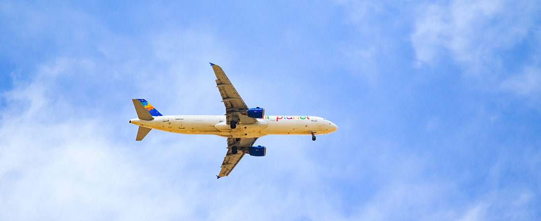 Un avión de pasajeros volando a gran altura en un cielo azul y despejado, visto desde abajo.